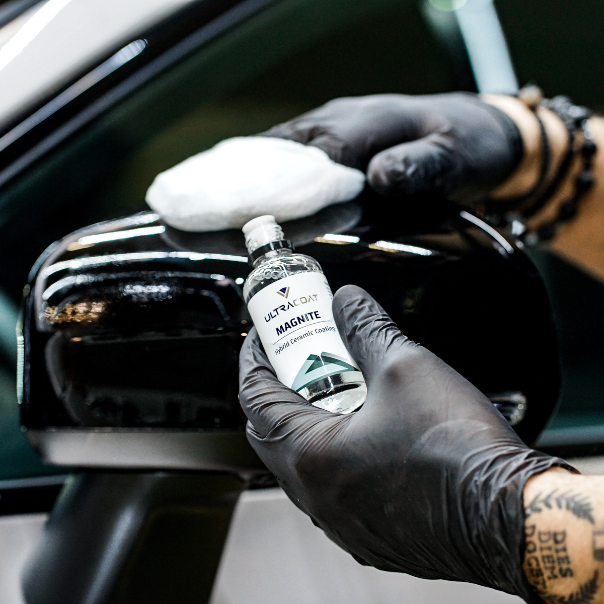 Gloved hand applying Ultracoat Magnite to a vehicle's chrome grille using a white applicator pad