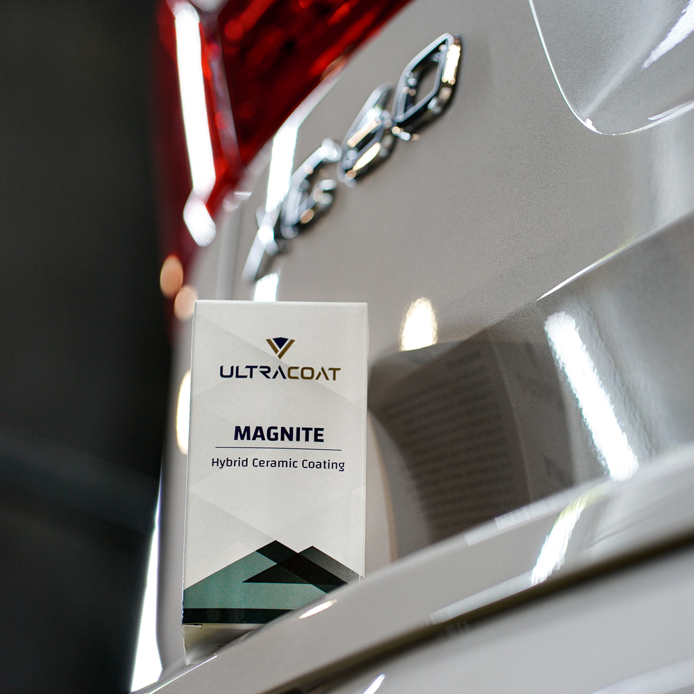 Ultracoat Magnite retail packaging resting against a vehicle's rear bodywork, next to chrome trim and a tail light