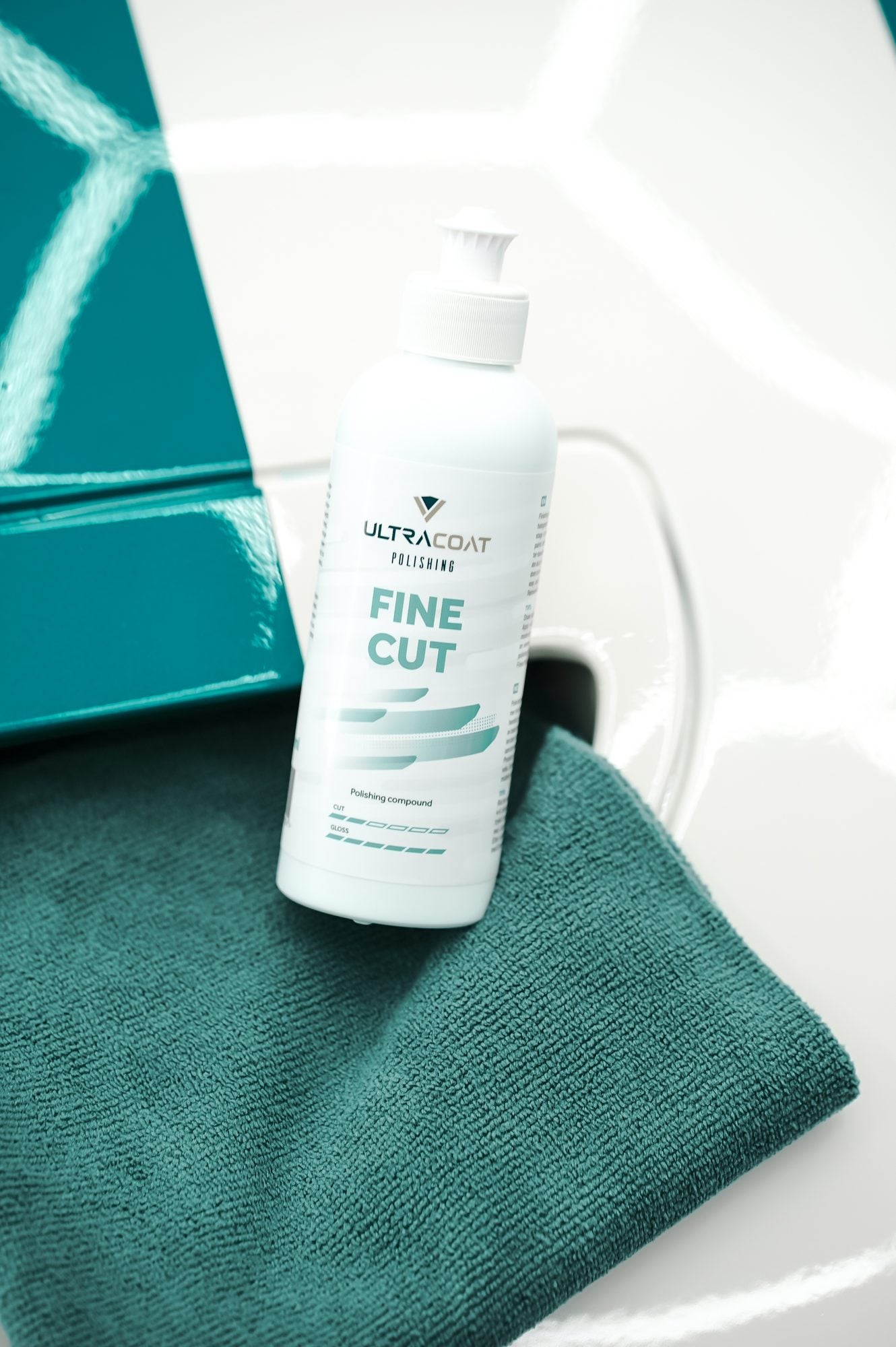 Ultracoat Polishing Fine Cut bottle with teal microfibre cloth on a white vehicle with teal accent