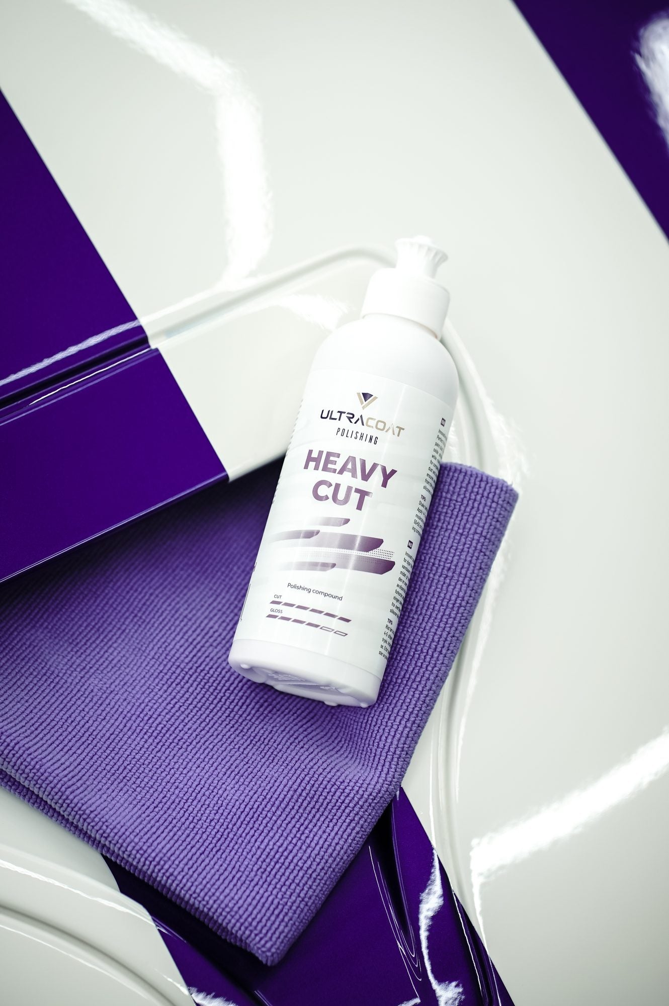 Ultracoat Polishing Heavy Cut bottle with purple microfibre cloth on a white vehicle with purple accent