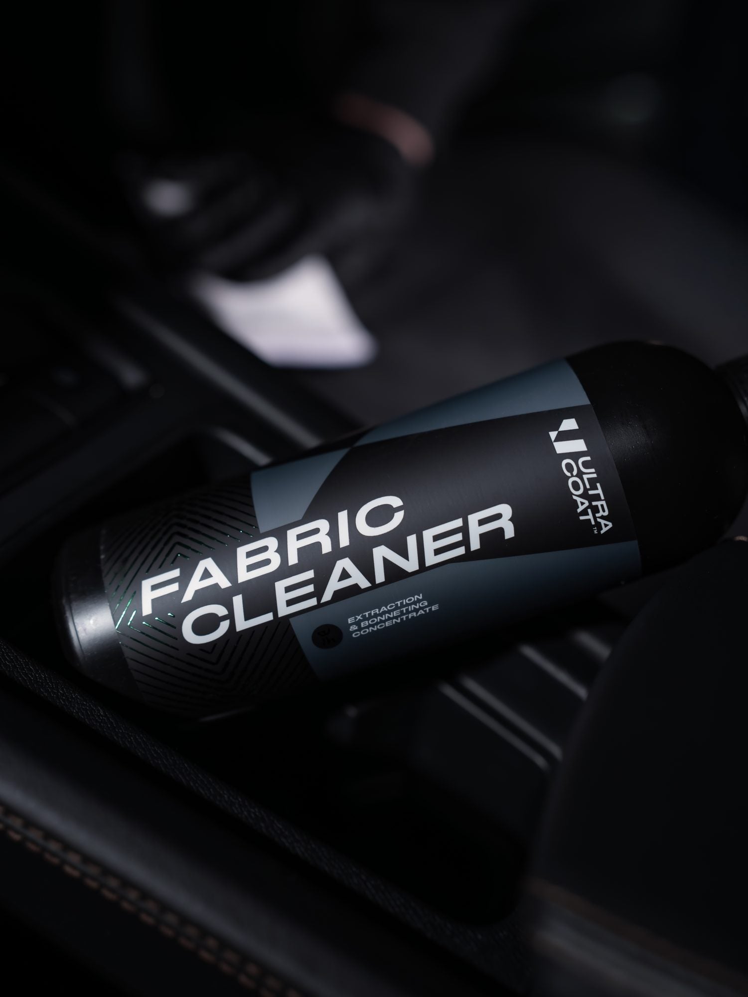 Ultracoat Fabric Cleaner resting in a vehicle footwell