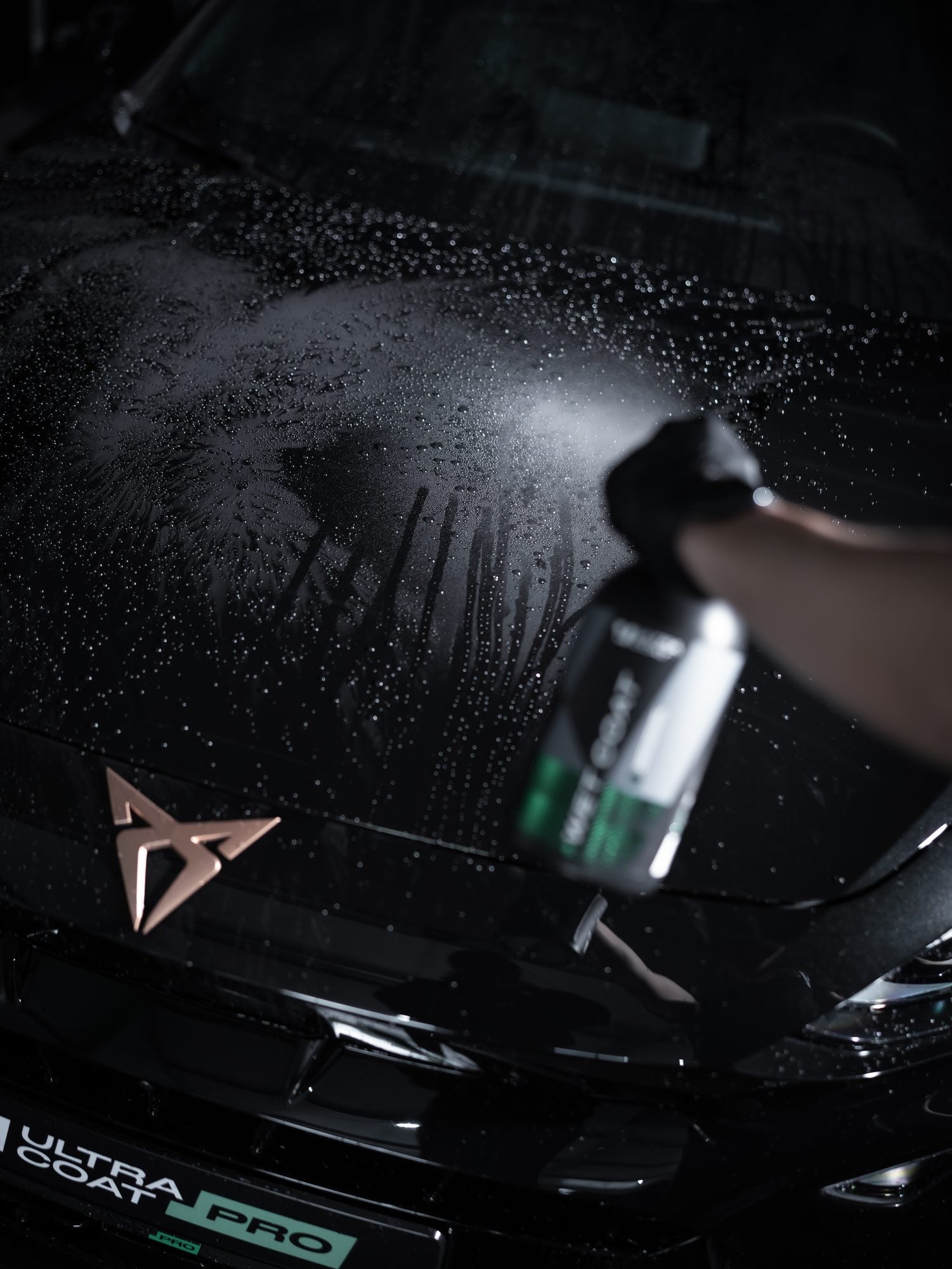 Ultracoat Wet Coat SiO2 sealant sprayed onto the wet exterior of a black vehicle