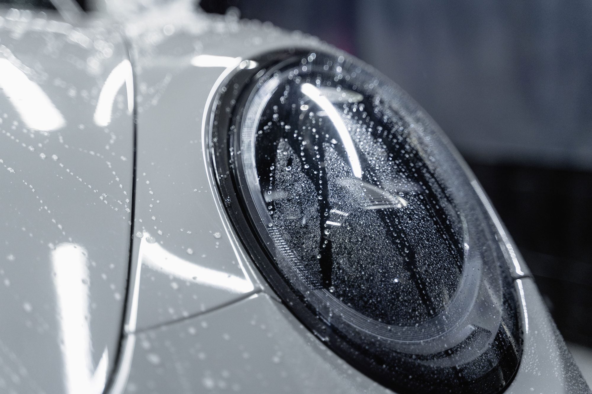 Close-up of a glossy, water-beaded headlight after detailing