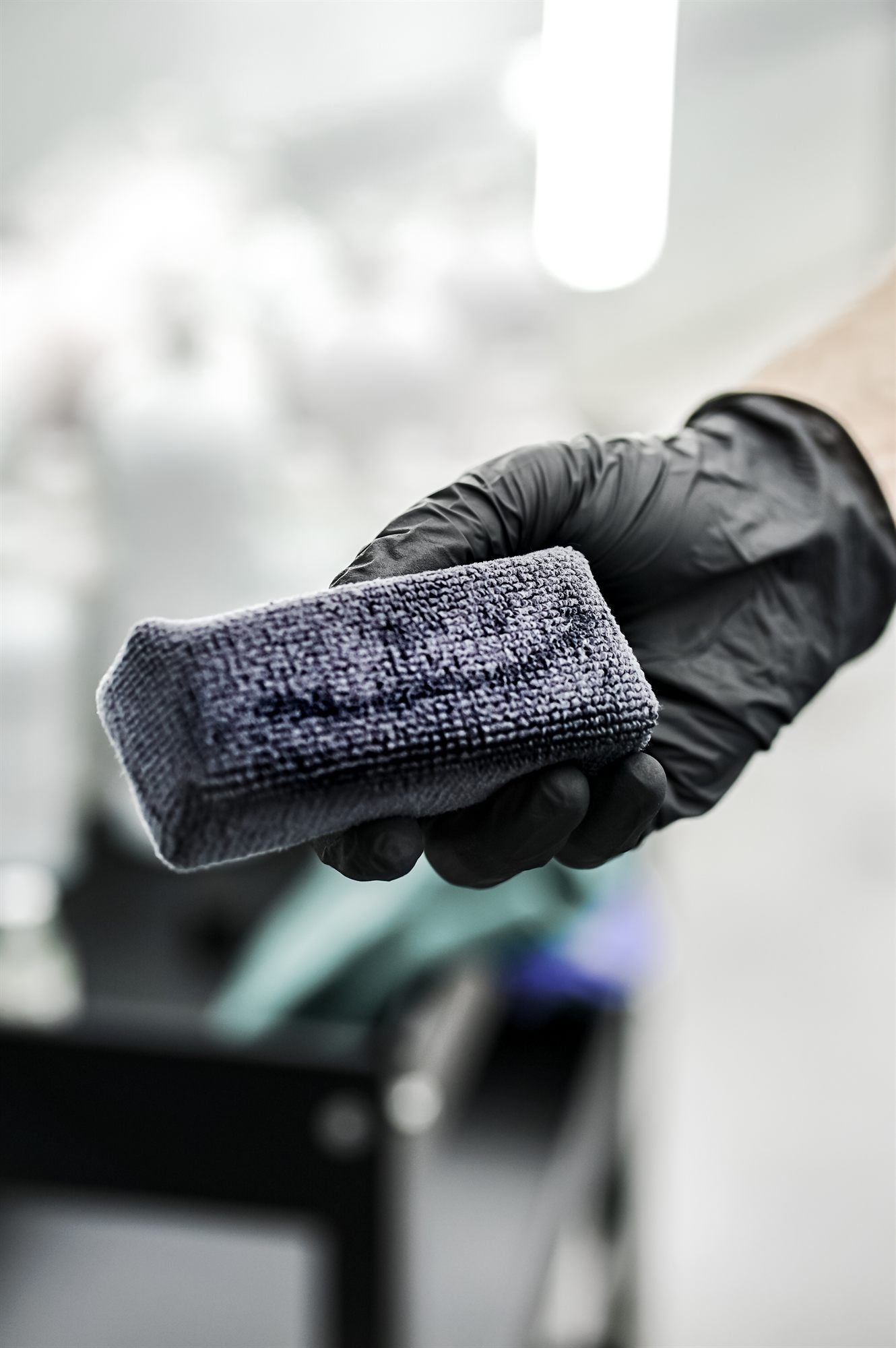 Gloved hand holding a ceramic coating applicator pad